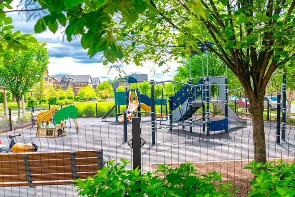 Parlak renkli oyun ekipmanları, eskrim, banklar ve peyzaj ile çocuk parkı.