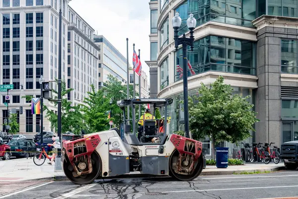 Şehirdeki kaldırımları onarıyorum. Bir yol silindiri yeni asfalt seriyor.
