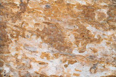 Yıpranmış taş plaka üzerinde pas ve aşınma. Sert, kahverengi ve turuncu tonlarda çukurlaşmış doku..