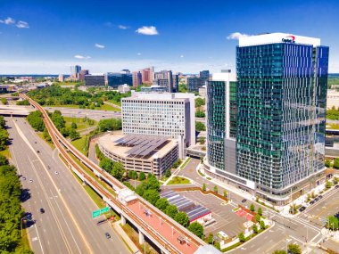 Otoyolun havadan görünüşü, Tysons Metro hattı ve istasyonu, gökdelenler ve mavi gökyüzü..