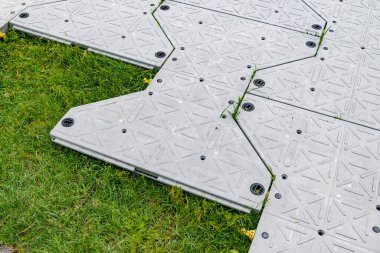 Çimenlikteki çimleri korumak için koruyucu plastik fayanslar.