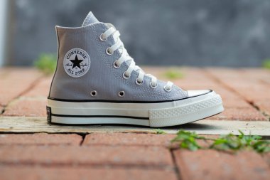 Stylish Gray Canvas Sneakers Converse rustic tuğla yüzeyinde gündelik unisex ayakkabılar.