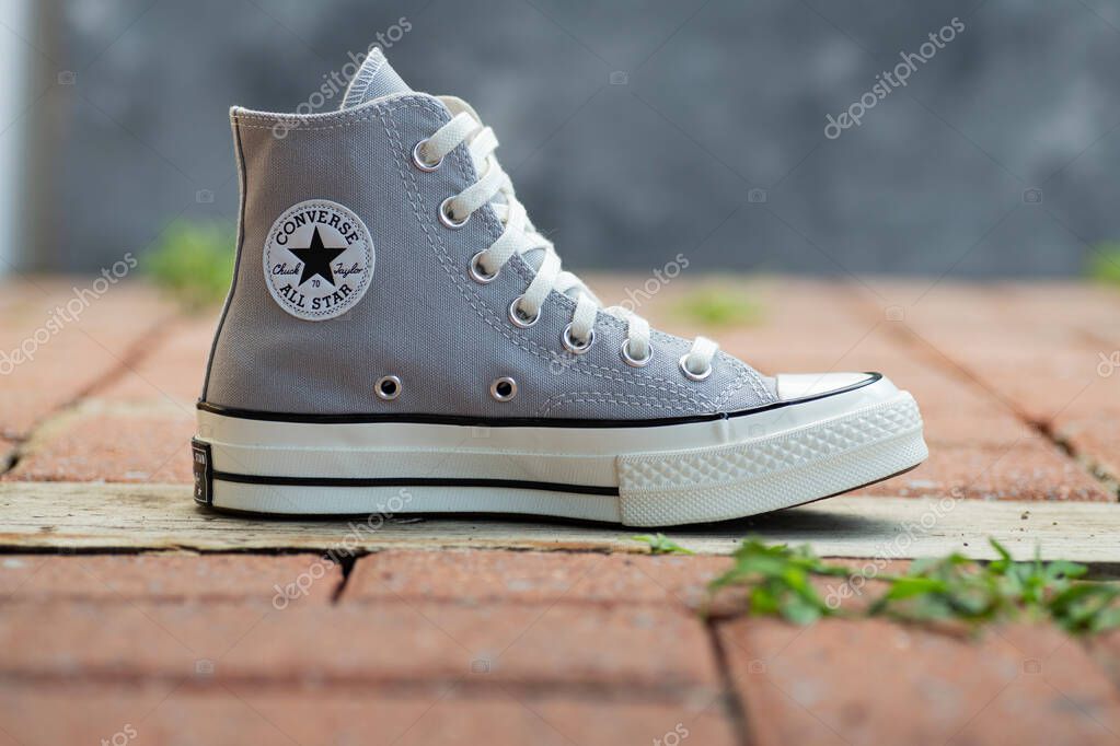 Stylish Gray Canvas Sneakers Converse.. Casual unisex shoes on rustic brick surface.