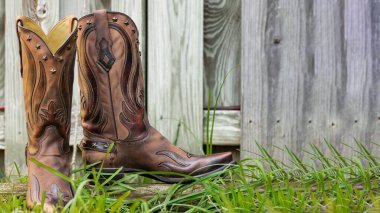 Deri Kovboy Çizmeleri ve Ahşap Doku. Doğal ışıkta köy yaşam tarzı sembolü.