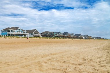 Kuzey Carolina 'daki Atlantik Okyanusu sahilinde yazlık evler. Kum ve mavi gökyüzü.