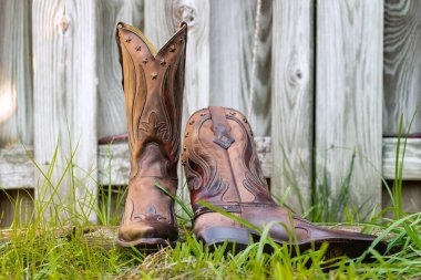 Klasik Kovboy Çizmeleri Açık havada. Tahta çitlerin yanında kahverengi deri çizme.
