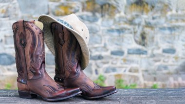 Taş duvar arkaplanından elle işlenmiş kovboy çizmeleri. Metin için yer.