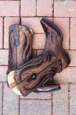 Bir çift el yapımı sığır derisi kovboy çizmesi kaldırımda.