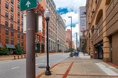 Yüksek binalı Baltimore caddesi manzarası. Modern kuleler, kırmızı tuğla cepheler ve şehir merkezindeki şehir geometrisi..