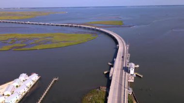 Körfezin karşısındaki Chincoteague kasabası ve Assateague Doğa Koruma Alanı 'na giden yol. Yol ve arabaların hava manzarası