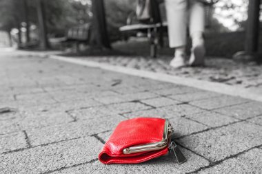 Paralı kırmızı cüzdan, kaldırımda bir parkta. Kaldırımda unutulmuş bir cüzdanın yakın çekimi..
