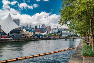 Modern Baltimore Limanı mavi gökyüzünün altında. Rıhtım ve beyaz tenteler şık bir liman havası yaratıyor..