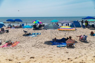Çadırlar ve ailelerle turist plajında sıcak güneşli bir gün.