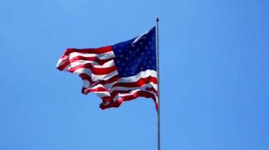 Güneşli bir günde açık mavi gökyüzüne karşı Amerikan Bayrağı sallıyor