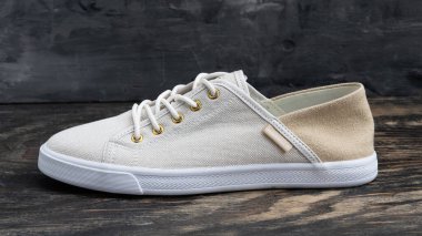 Tommy Hilfiger beyaz spor ayakkabıları logo etiketli ve tahta arka planda lastik tabanlı..