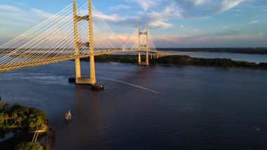 Yükselen asma köprü nehir boyunca uzanıyor. Akşam bulutları modern mühendisliğin dramını yansıtıyor..