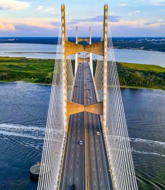 Gün batımında Jacksonville ikonik asma köprüsünün hava görüntüsü. Yansımalar aşağıdaki sakin nehirde parıldıyor