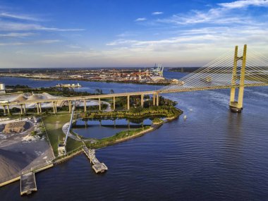 Yükselen asma köprü nehir boyunca uzanıyor. Akşam bulutları modern mühendisliğin dramını yansıtıyor..