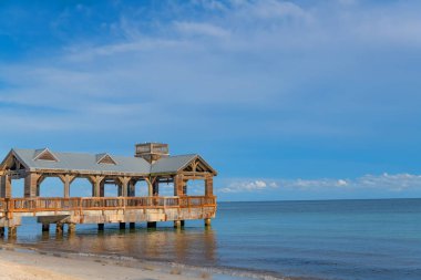 Scenic Gulf beach with rustic boardwalk extending into tranquil turquoise sea