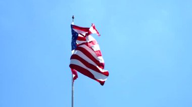 Açık mavi gökyüzünün altında gururla dalgalanan Amerikan bayrağı
