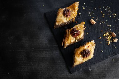 Siyah tabakta servis edilen şam fıstığı, ceviz, bal ve portakal şurubuyla ev yapımı baklava. Türk kültürü Türk mutfağı. Metin için yer