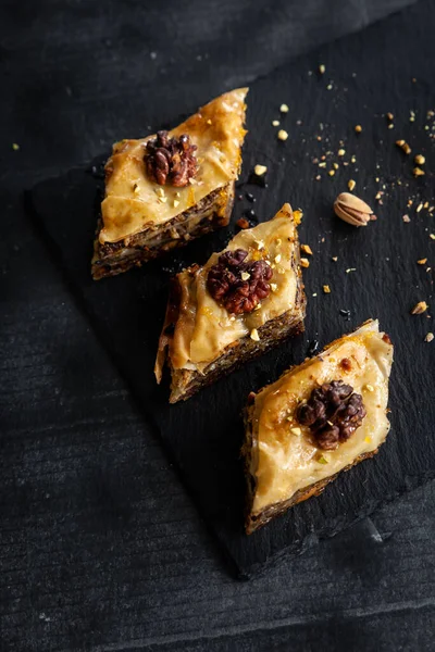 Homemade baklava with pistachios and walnuts and honey and orange syrup served in a black plate. Turkish culture Turkish cuisine. Place for text