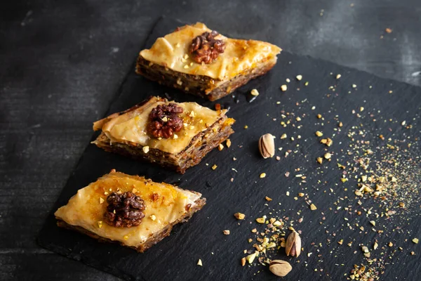 Homemade baklava with pistachios and walnuts and honey and orange syrup served in a black plate. Turkish culture Turkish cuisine
