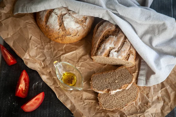自家製ライ麦パン リネンナプキンとクラフト紙のオリーブオイルとトマト — ストック写真