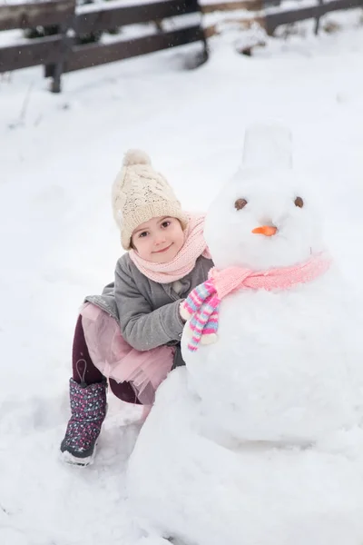 Дівчина Грає Сніговиком Рожевим Язаним Шарфом Зимовому Саду — стокове фото