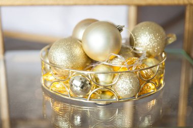 Altın sarısı bir fiyonk, parlak arka planı ve yansıması olan altın Noel toplarıyla dolu. Noel atmosferi yaratıcı kavramı