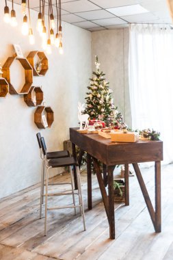 Konforlu bir oturma odası ya da ekolojik dekorlu bir stüdyo. Odanın içinde ahşap ve doğa kavramı. İskandinav iç mimarisi, noel ağacı, ahşap Fransa rafları, gerçek fotoğraf. Hygge dekorasyonu.