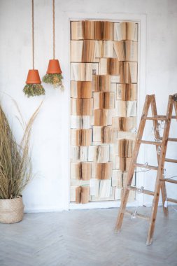 Işık duvarında kitaplar, ahşap merdiven ve bitkilerle çevrilmiş kil çömlek şeklinde avize olan şık bir stüdyo dekoru.
