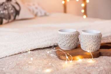 Tahta desenli, geyik boynuzları ve iki fincan sıcak xmas örülmüş süveter ile bir yatakta kesme tahtası.