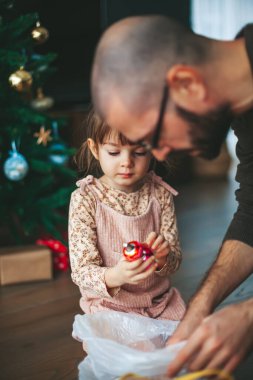 Şirin küçük kız ve babası Noel ağacına süsler asıyorlar.