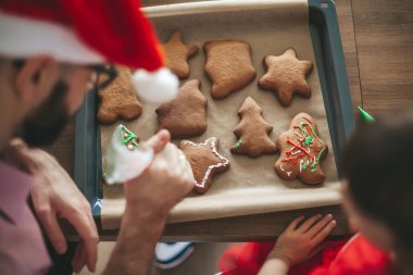 Babası ve küçük kızı zencefilli çörekleri süslüyor. 