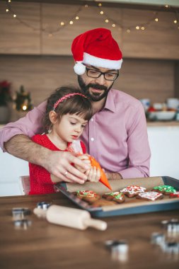 Aile dekorasyonu zencefilli Noel kurabiyeleri. Baba ve kızı Noel ve yeni yıl kutlamalarına hazırlanıyor..