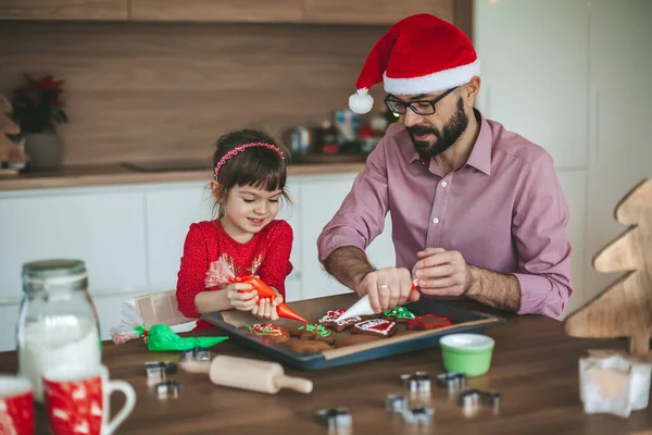 귀여운 소녀와 그녀의 아버지가 생강빵 크리스마스 쿠키꾸미는 즐거움을 누리는 — 스톡 사진