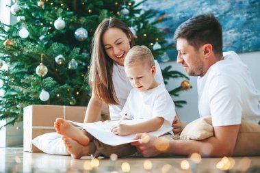 Küçük çocuk yanında ailesi otururken Noel Baba 'ya mektup yazıyor. Aile, Noel ağacının yanındaki hediyelerle ilgili rüyalar yazıyor. Mutlu Noeller ve mutlu yıllar.!