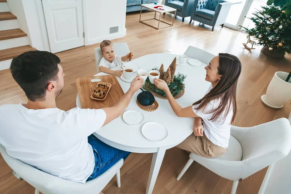 圣诞节的早晨 一家人坐在餐桌旁 快乐极了 爸爸和他们的小儿子喝茶 吃蛋糕当圣诞早餐 — 图库照片