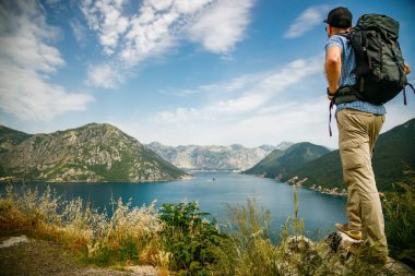 Bir uçurumun kenarında duran turist, Karadağ 'ın Kotor Körfezi manzarasının tadını çıkarıyor