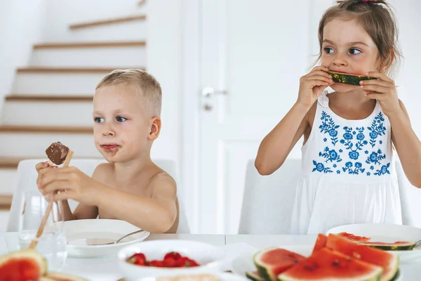 两个小孩在厨房里吃新鲜多汁的西瓜和冰淇淋 — 图库照片