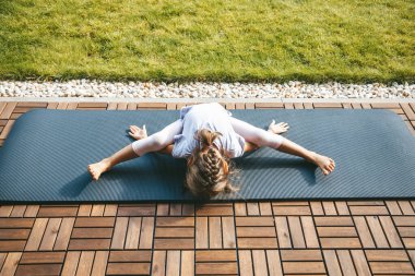 Kaplumbağa pozisyonunda yatan küçük kız mı yoksa Kurmasana 'nın dışarıda yoga yapması mı? Çocuklar için yoga. Çocuğun sağlıklı yaşam tarzı..