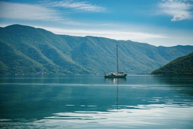 Kotor Körfezi 'nde arka planda dağlar olan bir yatın güzel manzarası, Karadağ