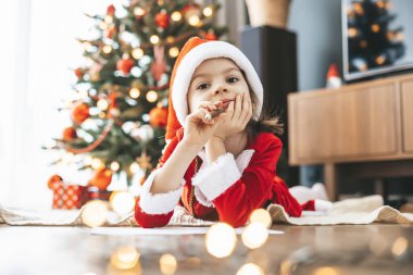 5-6 yaşlarında, Noel Baba 'nın şapkasıyla Noel Baba' ya dileklerini yazan tatlı bir kız. Gözleri hayallerle dolu.