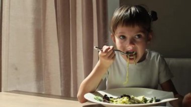 Bir kafede spagetti yiyen 5-6 yaşlarında tatlı bir kız.