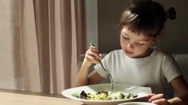 Sevimli küçük kız 5-6 yaşlarında peynirli spagetti yiyor.