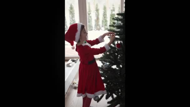 Lächelndes Kleines Mädchen Hängt Schmuck Und Christbaumkugeln Den Weihnachtsbaum Lizenzfreies Stock-Filmmaterial