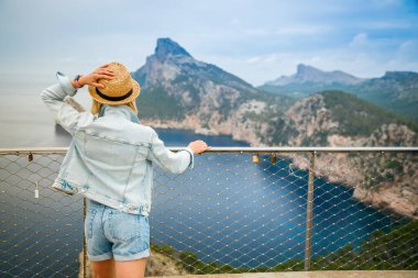 Hasır şapkalı kadın Mallorca, İspanya 'daki Cap de Formentor' un güzel manzarasının keyfini çıkarıyor.