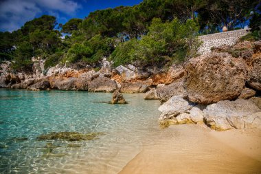 Mallorca 'daki rahat Cala Gat plajı, kumlu sahili, turkuaz denizi ve taş uçurumları sergiliyor.