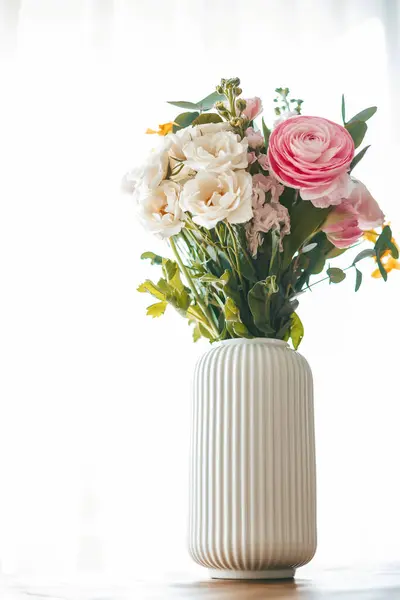 さまざまな形やサイズの花のカラフルな花束は リブ付きの白い花瓶を飾ります ストック画像